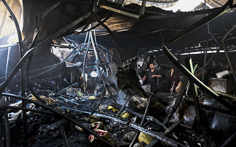 Bangladeshi shop owners look at their burnt belongings after a fire break out in a makeshift market in Dhaka on 30 March, 2019. Photo: AFP