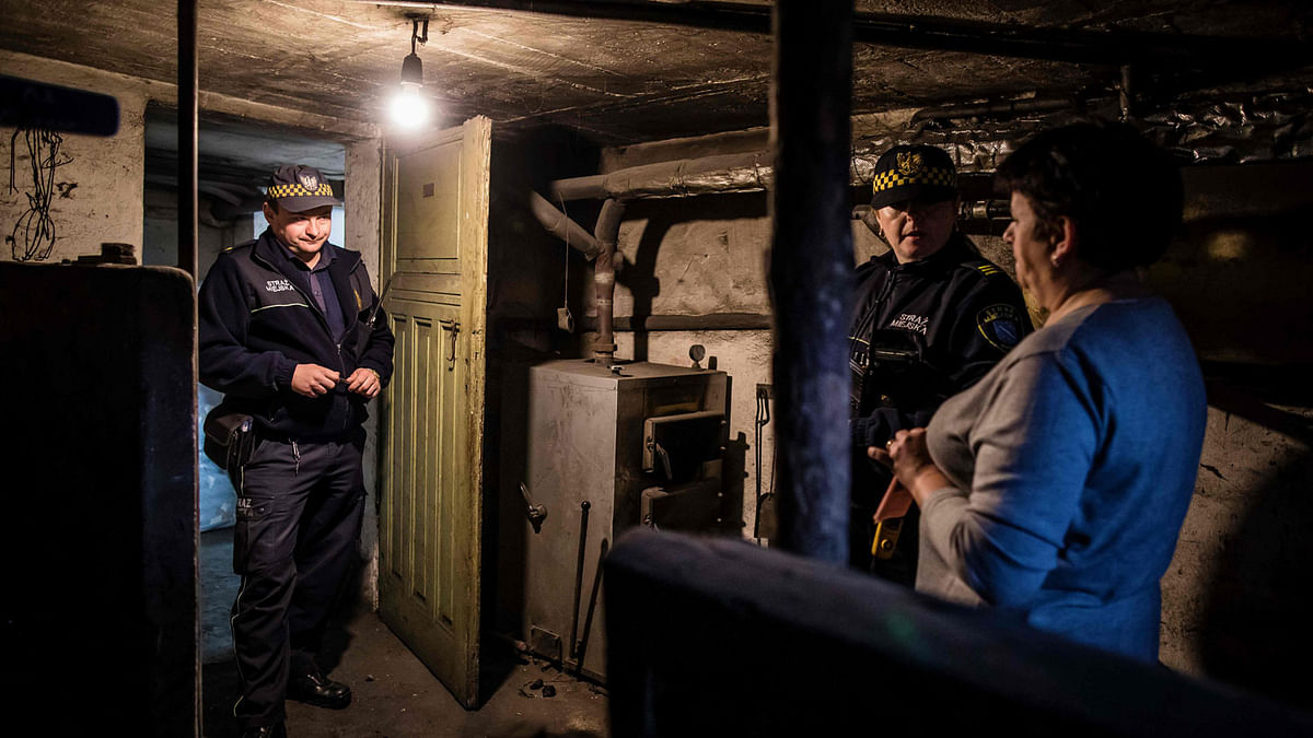 Katarzyna Klosok (2ndR) and Slawomir Jarzabek (L) of the municipal police in charged with sniffing out residents illegally burning highly polluting rubbish pay a visit to Ewa Kempny and check her stove after they received an anonymous tip-off about the odd colour of smoke emerging from Kempny`s chimney on 15 March 2019 in the southern Polish coal mining town of Rybnik. Photo: AFP
