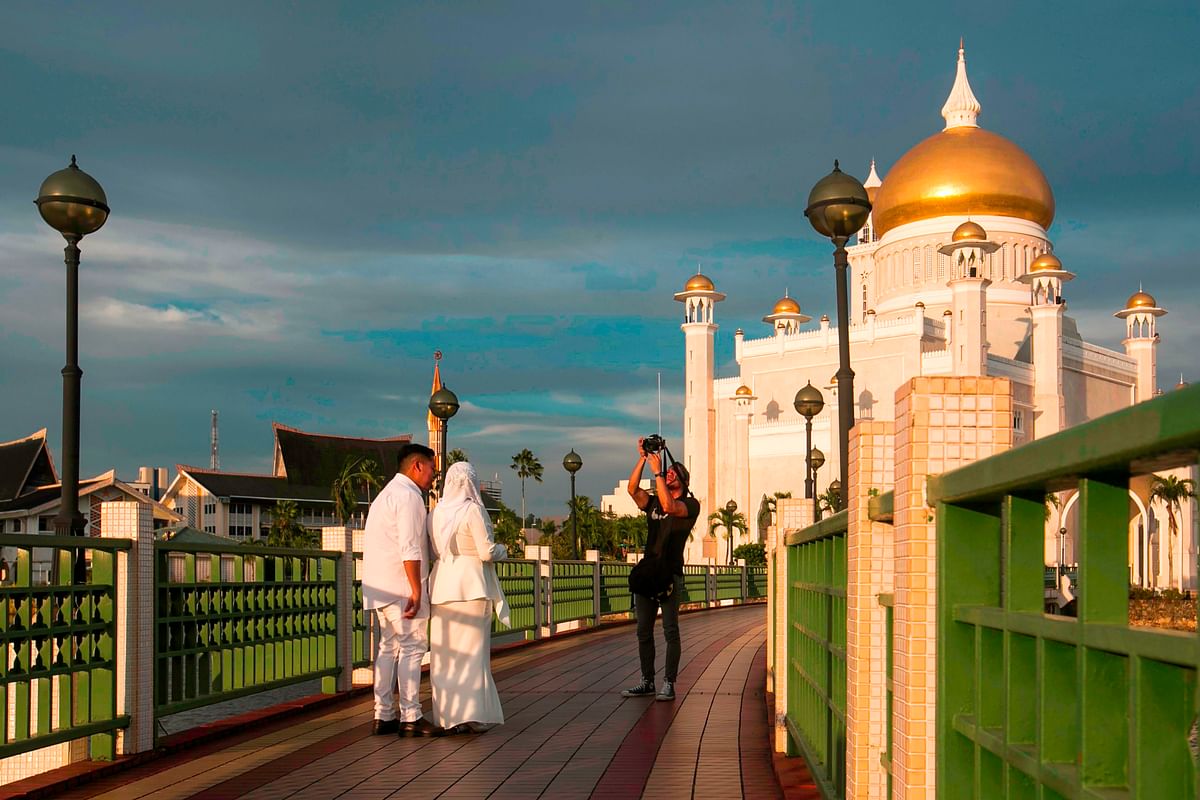 In this picture taken on 1 April 2019 a newlywed couple has their photographs taken at the Sultan Omar Ali Saifuddien mosque in Bandar Seri Begawan. Photo: AFP