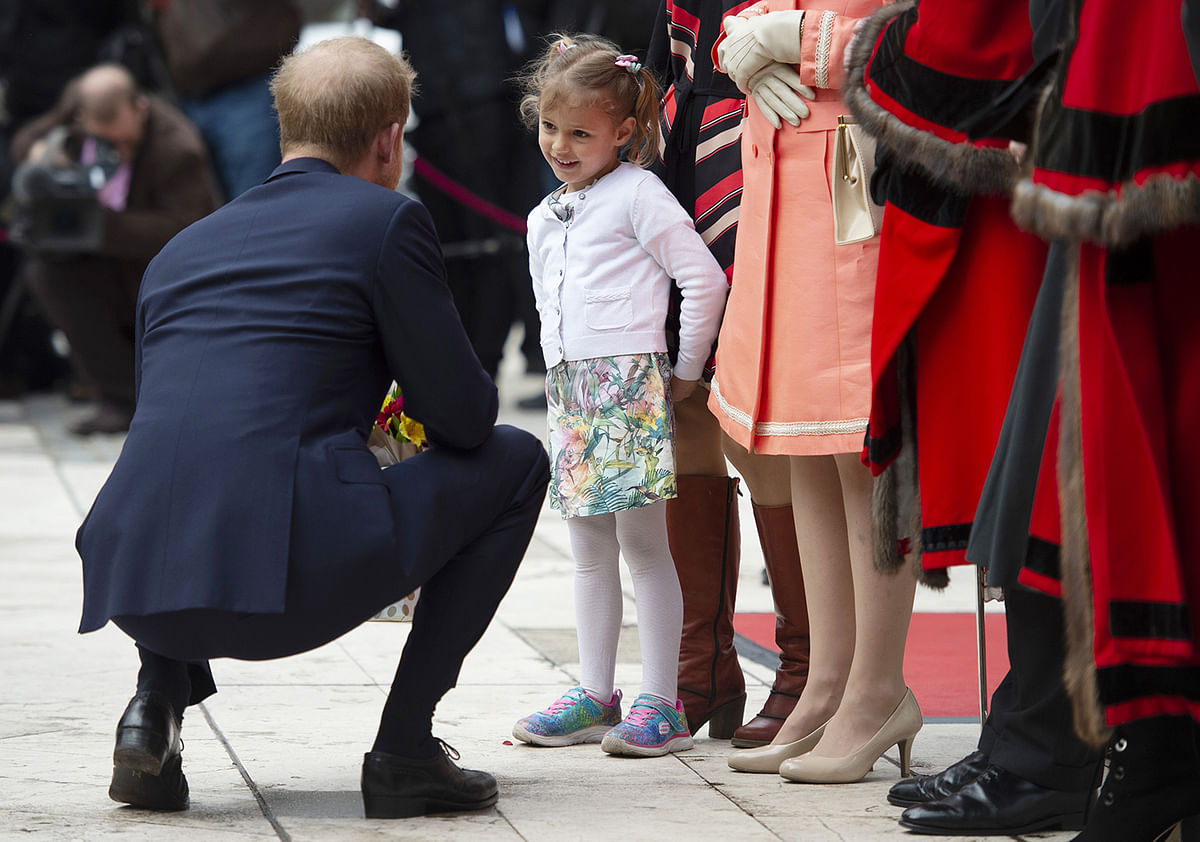 Britain`s prince Harry, Duke of Sussex is presented with a posy of flowers by four year-old Zofia Zdenkowska (R) at the twelfth annual Lord Mayor’s Big Curry Lunch, hosted by lord mayor of the city of London, Peter Estlin at The Guildhall in London on 4 April, 2019. Photo: AFP