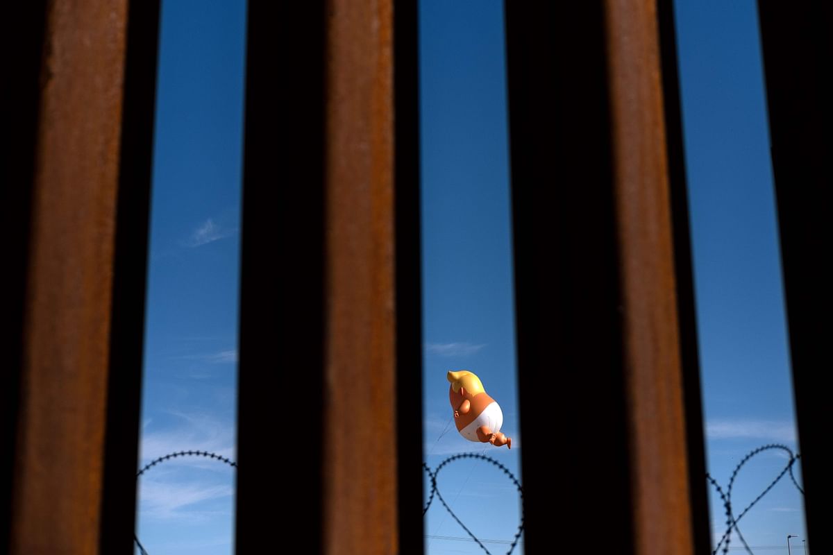 A satirical balloon of a baby US president Donald Trump is seen through the US-Mexico border fence during a demonstration against him prior to his visit to Calexico, California, as seen from Mexicali, Baja California state, Mexico, on 5 April 2019. Photo: AFP