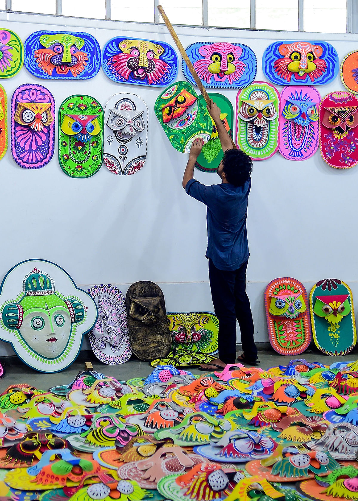 A Bangladeshi student of the Art Institute of Dhaka University hangs colourful masks for sale in preparation for the Bengali New Year celebration, in Dhaka on 7 April 2019. Photo: AFP