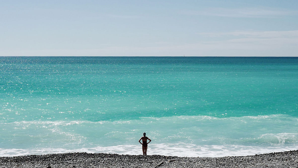 A woman stands in front of the Mediterranean Sea on the French Riviera city of Nice, on 4 April 2019. Photo: AFP