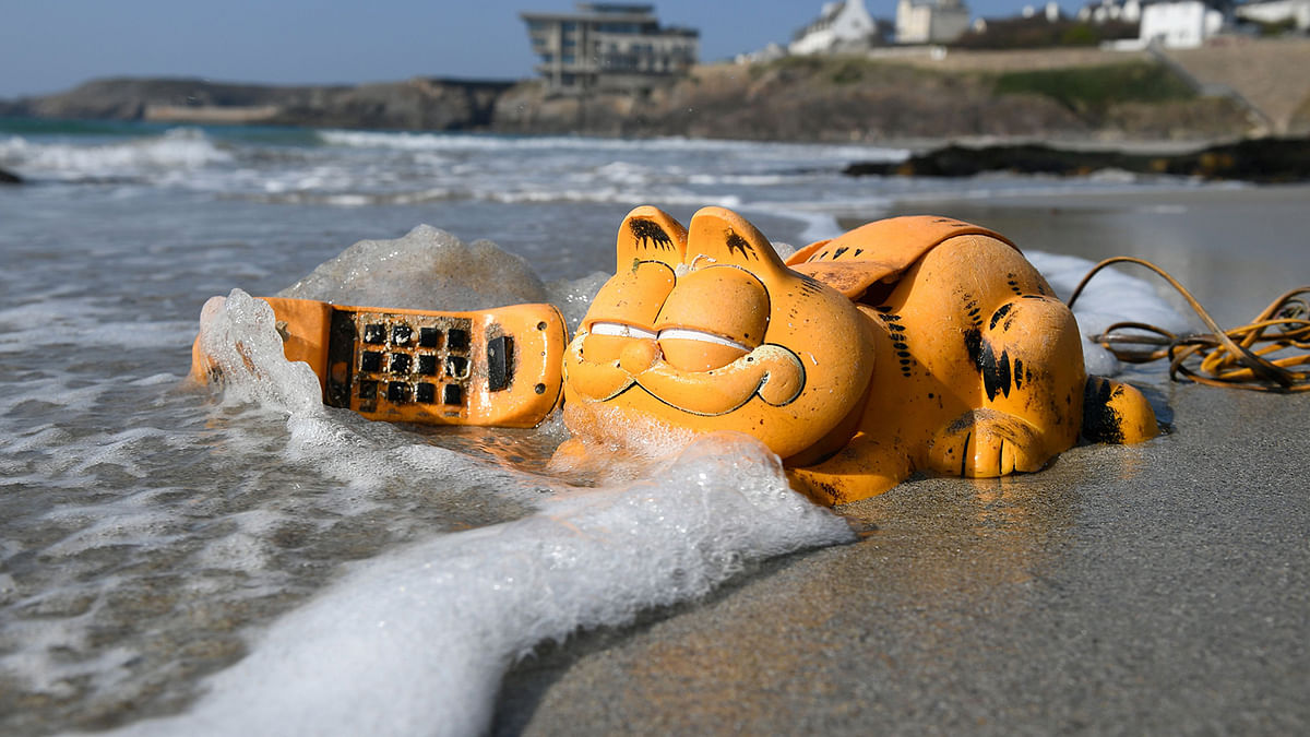 A plastic `Garfield` phone is displayed on the beach on 30 March 2019 in Le Conquet, western France. For more than 30 years, plastic phones in the shape of the famous cat `Garfield` have been washing up on French beaches. The mystery is now solved : a shipping container which washed up during a storm in the 1980s, was found in a hidden sea cave. Photo: AFP