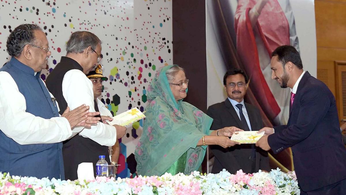 Prime minister Sheikh Hasina hands over cheques among the post-graduate students and researchers for research at a programme organised by the Ministry of Science and Technology at Bangabandhu International Conference Centre in Dhaka on Wednesday. Photo: PID