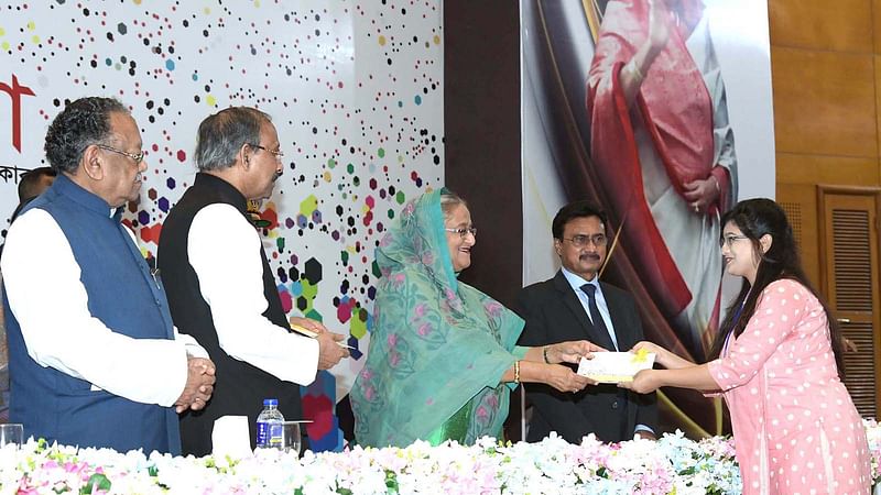 Prime minister Sheikh Hasina hands over cheques among the post-graduate students and researchers for research at a programme organised by the Ministry of Science and Technology at Bangabandhu International Conference Centre in Dhaka on Wednesday. Photo: PID