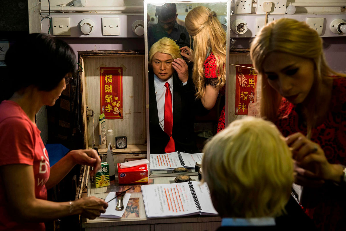 Actress Man Chan (R), dressed as Ivanka Trump, helps actor Loong Koon-tin (C), changes into US President Donald Trump back stage during a rehearsal of a Cantonese opera called `Trump on Show` in Hong Kong on 11 April 2019. Photo: AFP