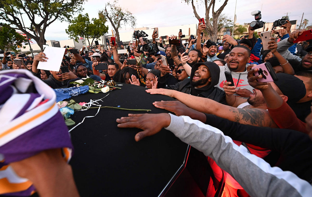 People touch the hearse carrying the remains of rapper recording artist and social activist Nipsey Hussle, as it arrives outside at the Angelus Funeral Home, the terminus of a 25-mile procession, on 11 April 2019 in Los Angeles, California. Photo: AFP