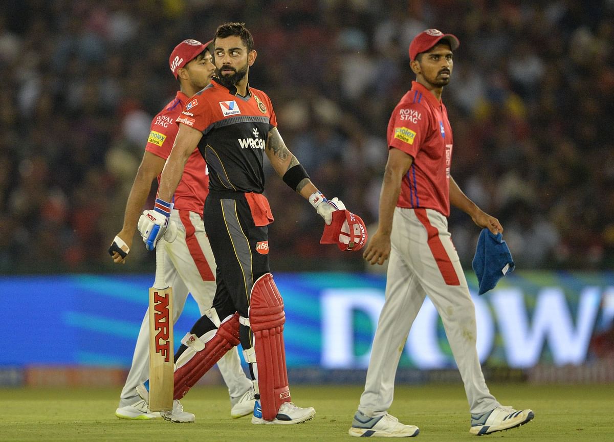 Royal Challengers Bangalore (RCB) cricketer and team captain Virat Kohli (C) walks back to the pavilion after he was dismissed during the 2019 Indian Premier League (IPL) Twenty20 cricket match between Kings XI Punjab and Royal Challengers Bangalore (RCB) at The Punjab Cricket Association Stadium in Mohali on 13 April 2019. Photo: AFP