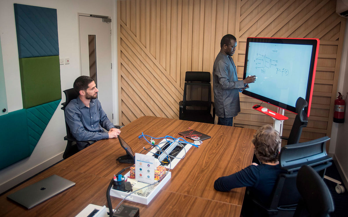 Moustapha Cisse ©, head of the Google Artificial Intelligence (AI) centre Ghana, talks with colleagues inside a meeting room in the Google AI office in Accra on 10 April 2019. This centre is the first AI centre established in Africa by Google. Photo: AFP