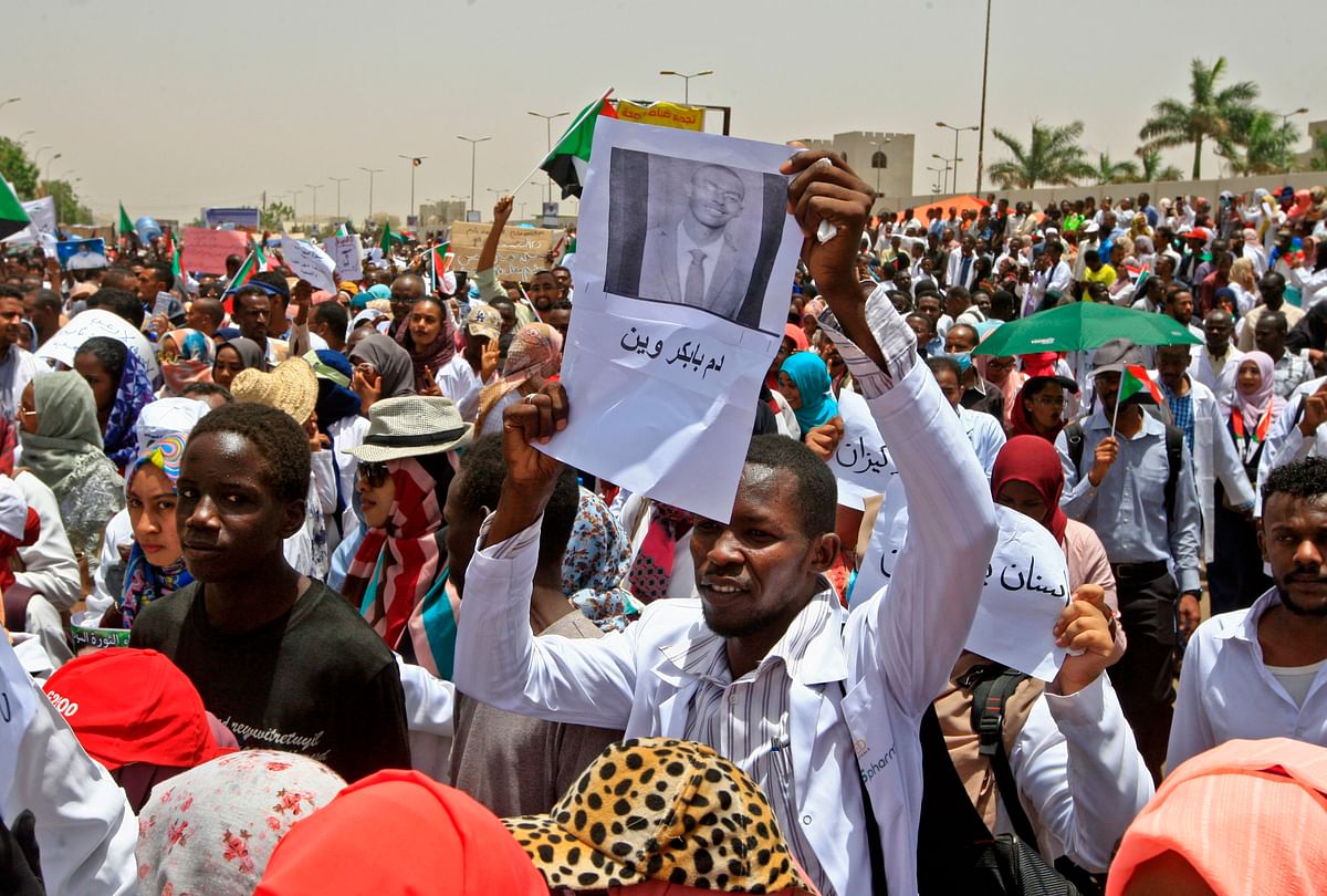 A Sudanese man holds up a sign with the name of a killed fellow protestor as demonstrators wave signs and flags while continuing to protest outside the army complex in the capital Khartoum on 17 April, 2019. Photo: AFP