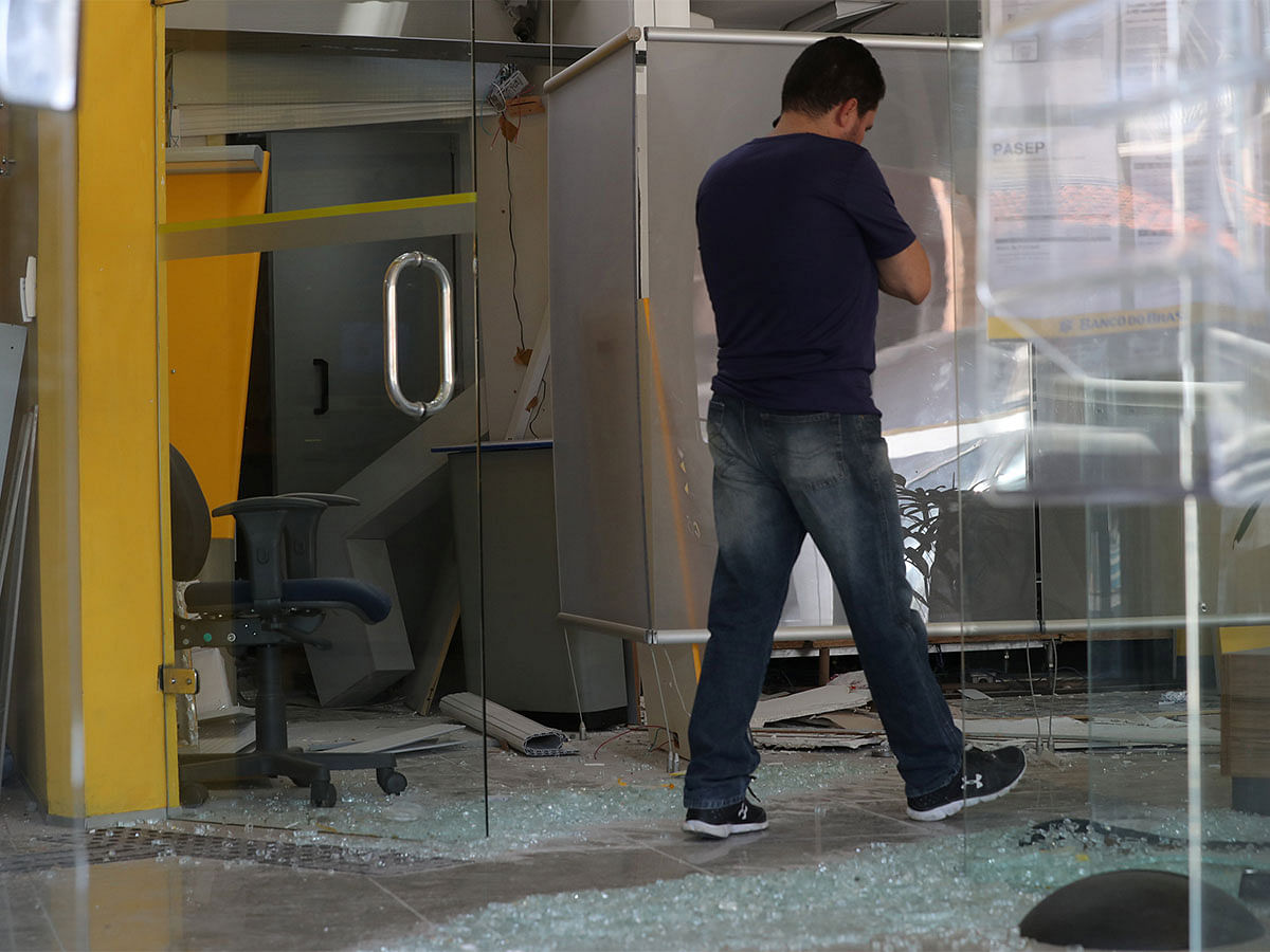 An employee walks next to broken glass at a damaged branch of Banco do Brasil after a gang caused an explosion in a part of the bank in an attempted robbery, in Guararema. Photo: Reuters