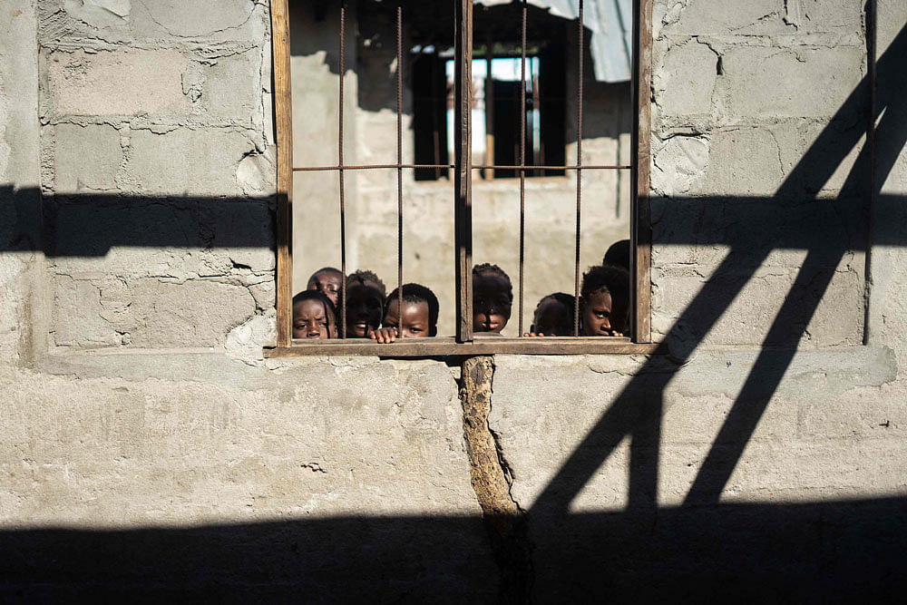 2School children peep through broken windows of a roofless, destroyed classroom at Guara-Guara Primary school, in Buzi district on 15 April 2019. Photo: AFP