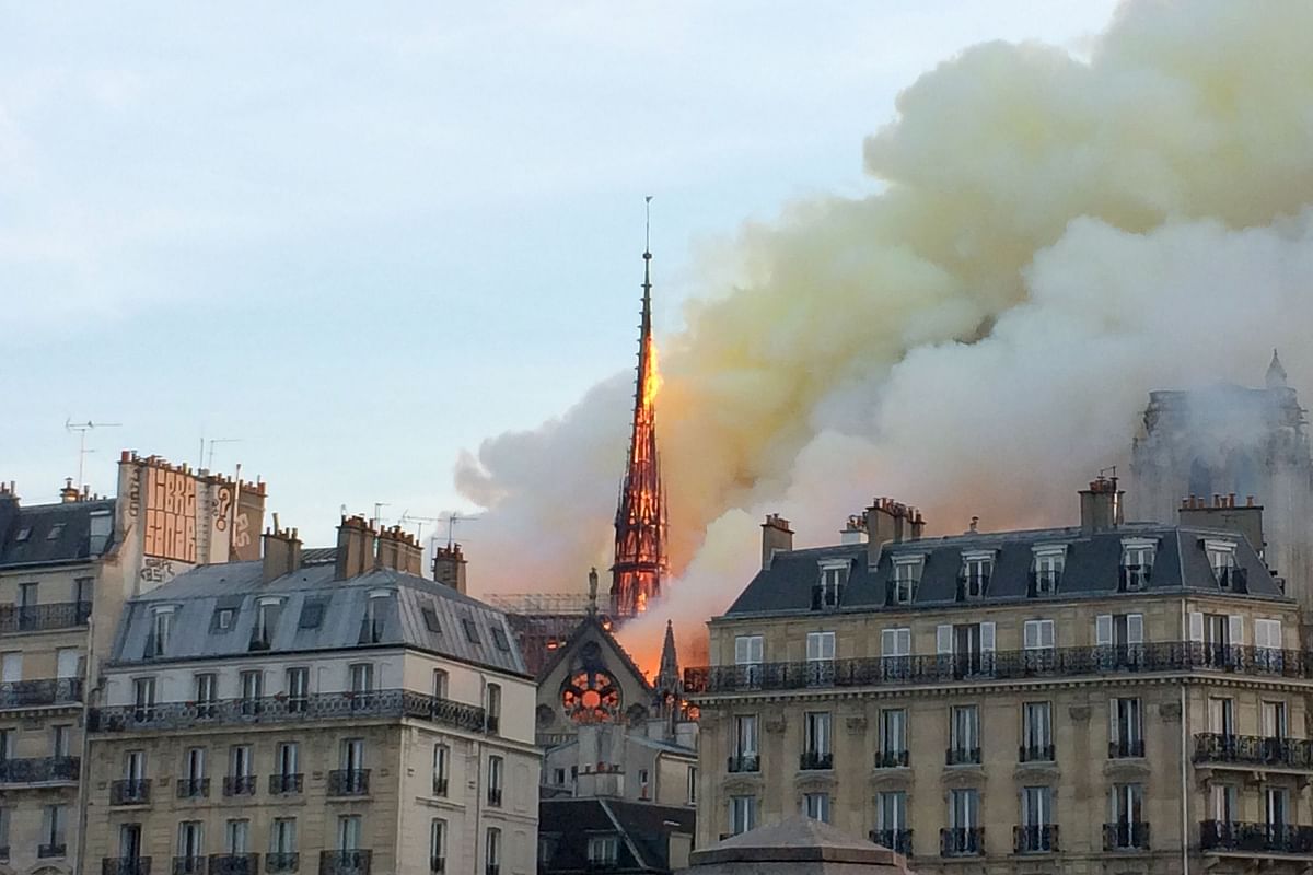 A picture taken with a mobile phone shows smoke and flames rising during a fire at the landmark Notre-Dame Cathedral in central Paris on 15 April, 2019, potentially involving renovation works being carried out at the site, the fire service said. Photo: AFP