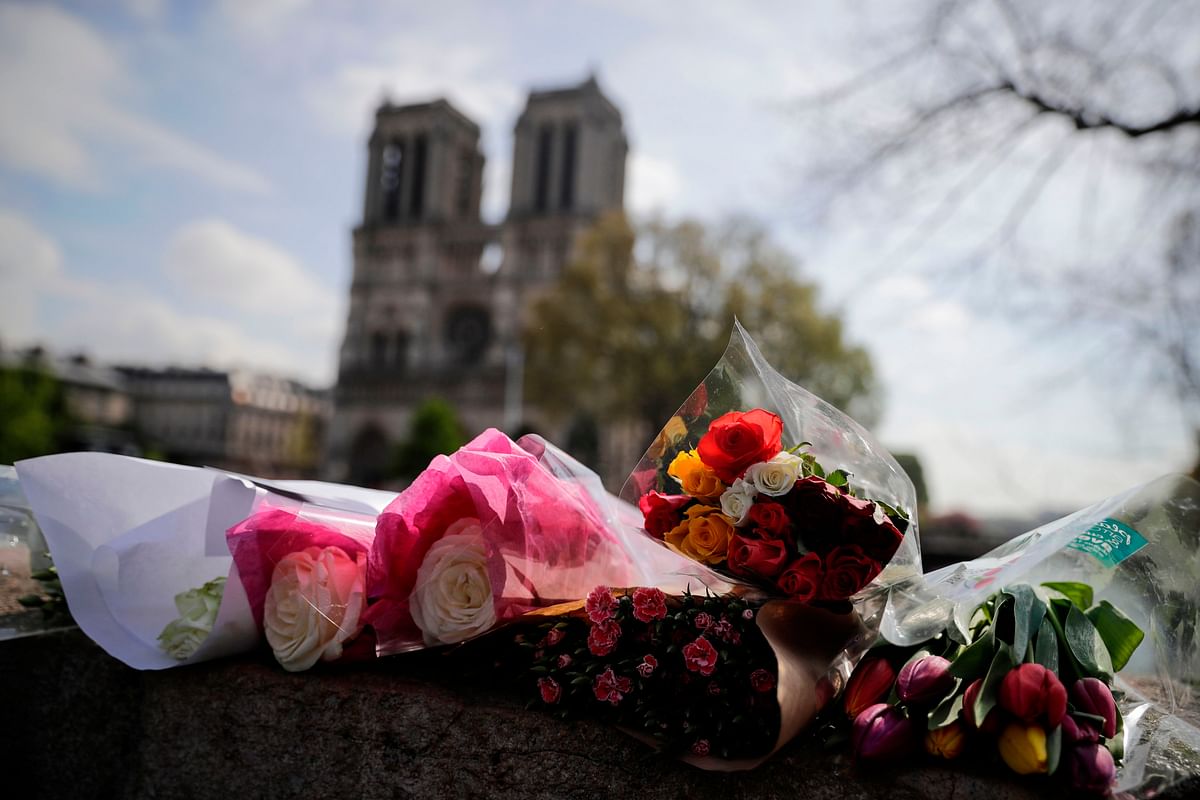 Flowers are laid on a bridge in front of the Notre-Dame-de Paris Cathedral in Paris on 17 April, 2019, two days after a fire that devastated the building in the centre of the French capital. Photo: AFP