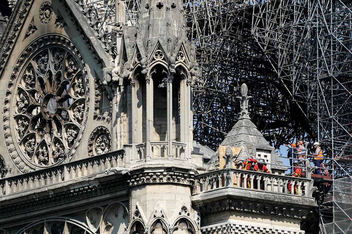 Firefighters and technicians work on a balcony of Notre-Dame de Paris Cathedral in Paris on 19 April, 2019, four days after a fire devastated the cathedral. Photo: AFP