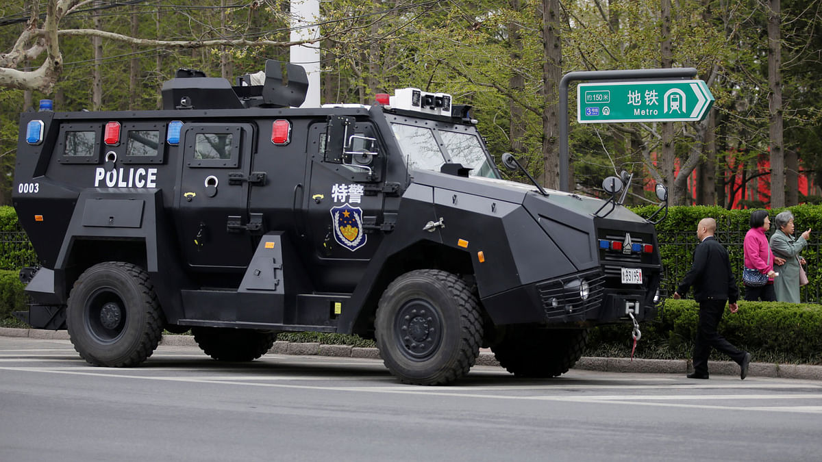Residents walk past a police armoured vehicle near a media centre for marking the 70th anniversary of the founding of the Chinese People`s Liberation Army Navy, in Qingdao, China, on 20 April 2019. Photo: Reuters