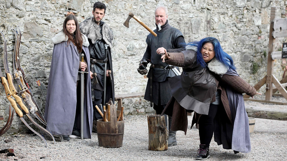 US Game of Thrones fan Jocelyn Vadli (R) tries axe throwing with Master of Arms Will van der Kells (2R) at the Castle Ward Estate in Strangford, northern Ireland, on 17 April 2019 the location of Winterfell in Game of Thrones, and one of the many locations used by the hit HBO show across the province. Photo: AFP