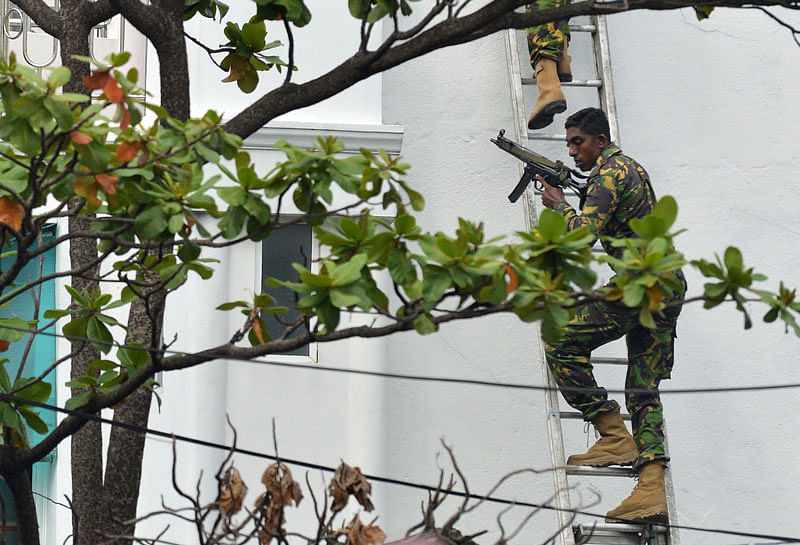 Sri Lankan Special Task Force (STF) personnel climb a ladder outside a house during a raid -- after a suicide blast had killed police searching the property -- in the Orugodawatta area of the capital Colombo on 21 April 2019, following a series of blasts in churches and hotels. Photo: AFP