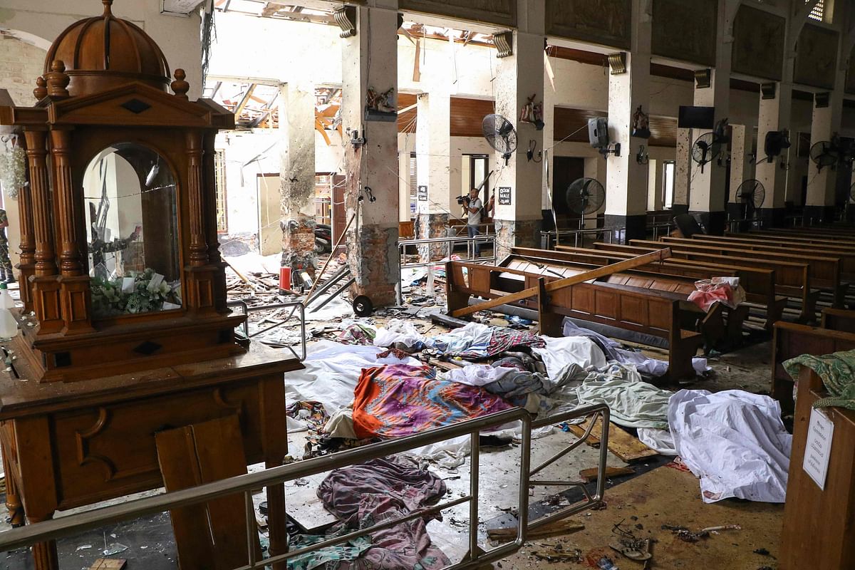 Sri Lankan security personnel walk past dead bodies covered with blankets amid blast debris at St. Anthony`s Shrine following an explosion in the church in Kochchikade in Colombo on 21 April 2019. Photo: AFP