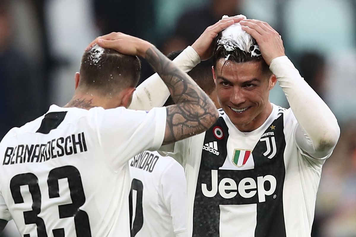 Juventus` Portuguese forward Cristiano Ronaldo (R) and Juventus` Italian forward Federico Bernardeschi, both with their head covered in foam, joke and celebrate after Juventus secured its 8th consecutive Italian 2018/19 `Scudetto` Serie A championships, after winning the Italian Serie A football match Juventus vs Fiorentina on April 20, 2019 at the Juventus stadium in Turin. AFP