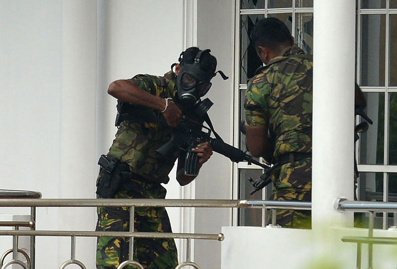 Sri Lankan Special Task Force (STF) personnel in gas masks are pictured outside a house during a raid -- after a suicide blast had killed police searching the property -- in the Orugodawatta area of the capital Colombo on 21 April 2019, following a series of blasts in churches and hotels. Photo: AFP