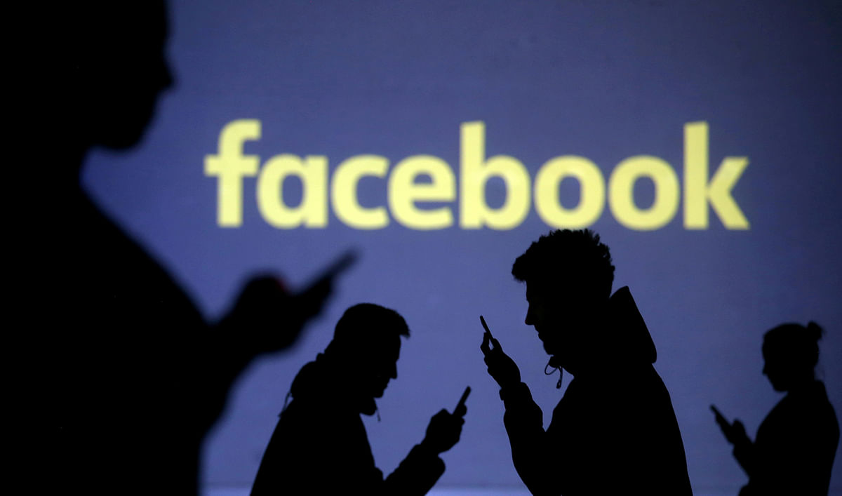 Silhouettes of mobile users are seen next to a screen projection of Facebook logo in this picture illustration. Photo: Reuters