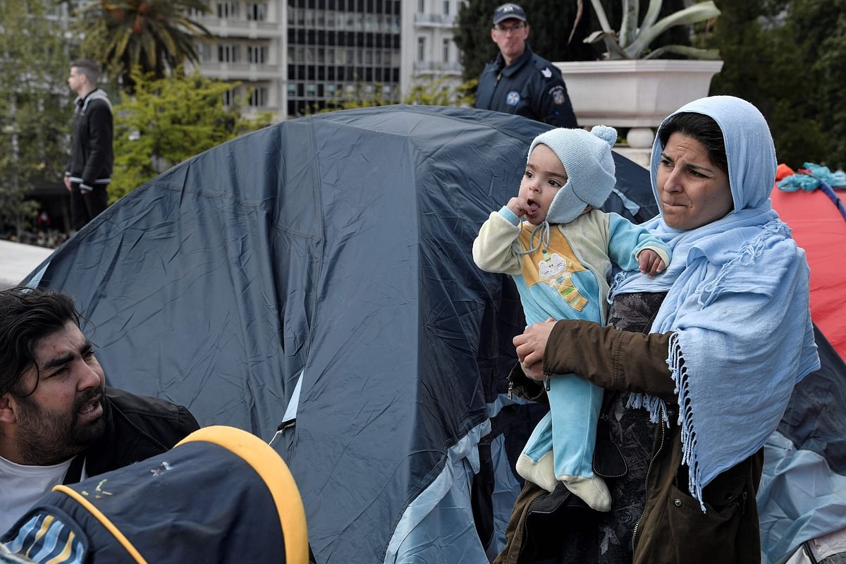 A migrant mother stands by a tent as a group of migrants and refugees camped out at the central Athens Syntagma square, on 19 April. Photo: AFP