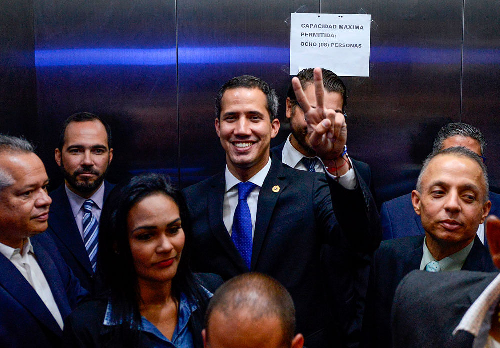 Venezuelan opposition leader and self-proclaimed interim president Juan Guaido (C) flashes the `Victory sign` as he leaves after presiding a consultation commission meeting at the Federal Legislative Palace, which houses both the opposition-led National Assembly and the pro-government National Constitutional Assembly, in Caracas on 16 April 2019. Photo: AFP