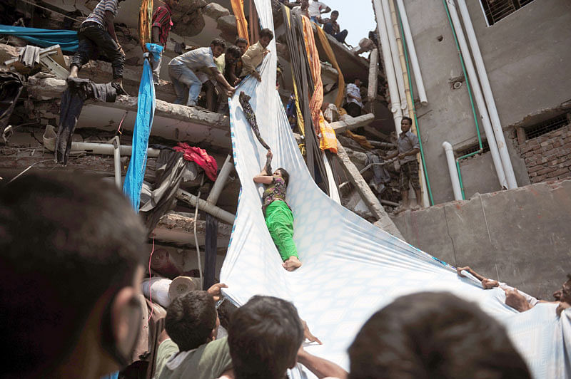 In this AFP file photo taken on 24 April 2013 Bangladeshi garment workers help evacuate a survivor using lengths of textiles as a slide to evacuate them from the rubble after an eight-storey building collapsed in Savar, on the outskirts of Dhaka. Photo: AFP