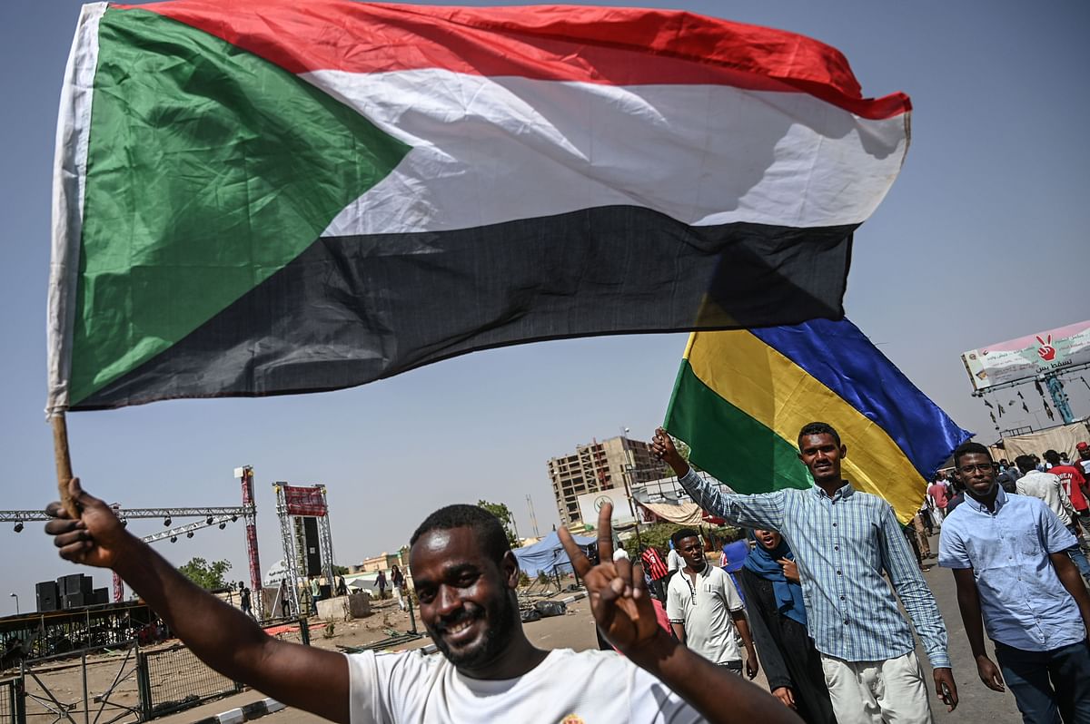 Sudanese protesters wave the current and former national flags during a rally outside the army headquarters in the capital Khartoum on 27 April. Photo: AFP