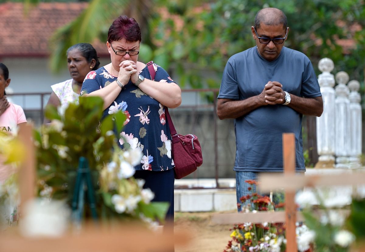 Relatives pay their respects in front of the graves of the victims of recent bomb blasts at St. Sebastian`s Church in Negombo on 28 April 2019, a week after a series of bomb blasts targeting churches and luxury hotels on Easter Sunday in Sri Lanka. Church bells tolled mournfully at Colombo`s devastated St Anthony`s Shrine on 28 April, as scores of Christians wept but defiantly prayed and lit candles for the victims of the horrific Easter bombings. Photo: AFP