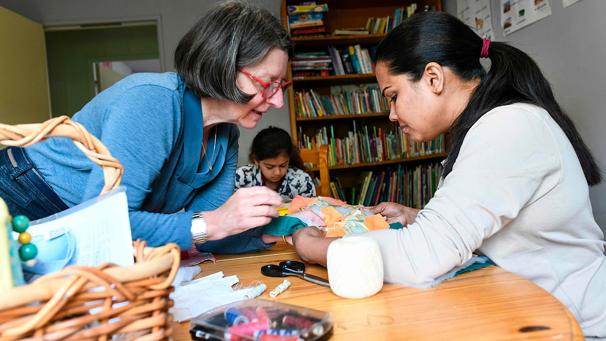 A volunteer (L) teaches a refugee how to sew in Ferrette, eastern France, on 24 April 2019. Photo: AFP