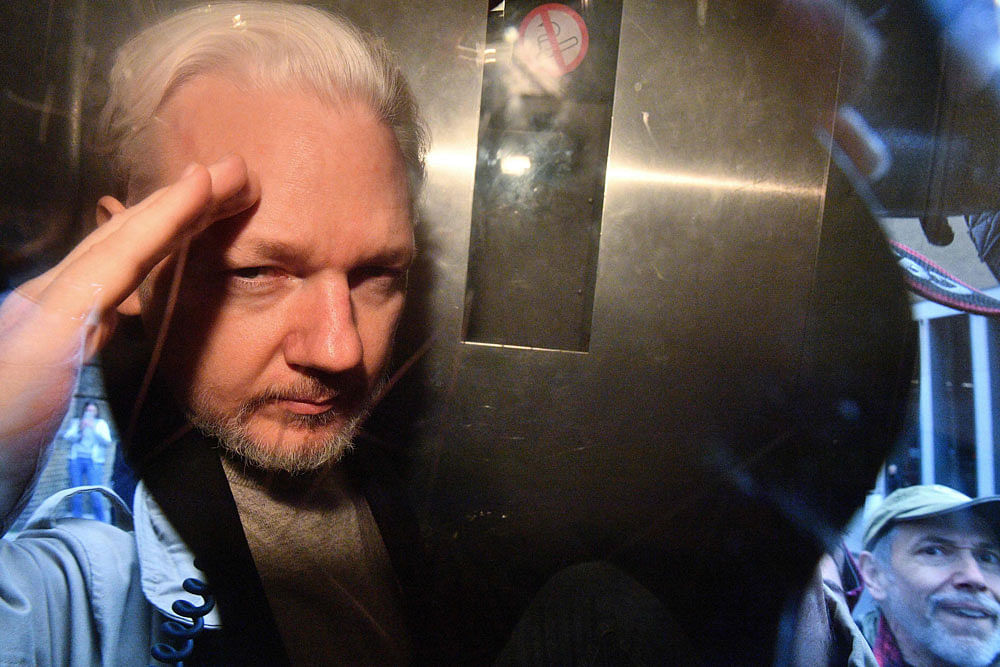 WikiLeaks founder Julian Assange gestures from the window of a prison van as he is driven out of Southwark Crown Court in London on 1 May, 2019, after having been sentenced to 50 weeks in prison for breaching his bail conditions in 2012. Photo: AFP