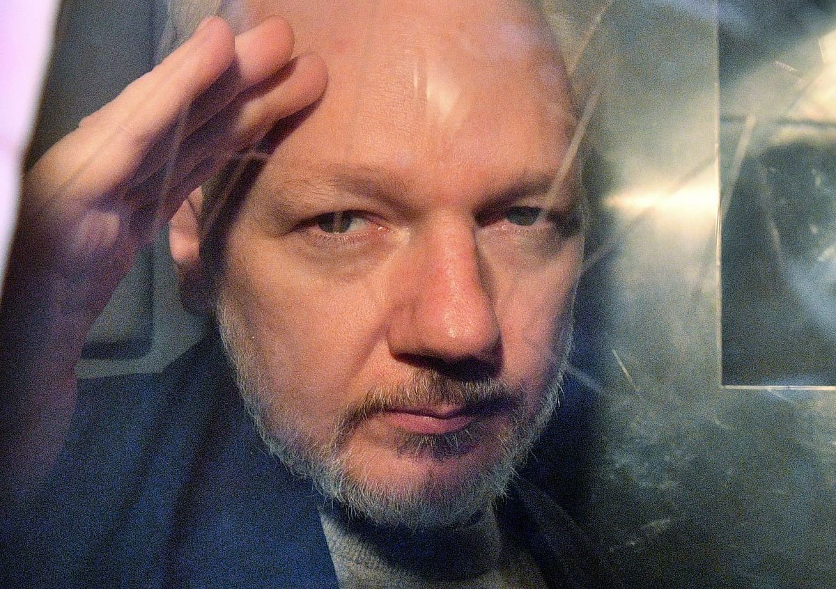 WikiLeaks founder Julian Assange gestures from the window of a prison van as he is driven out of Southwark Crown Court in London on 1 May 2019, after having been sentenced to 50 weeks in prison for breaching his bail conditions in 2012. Photo: AFP