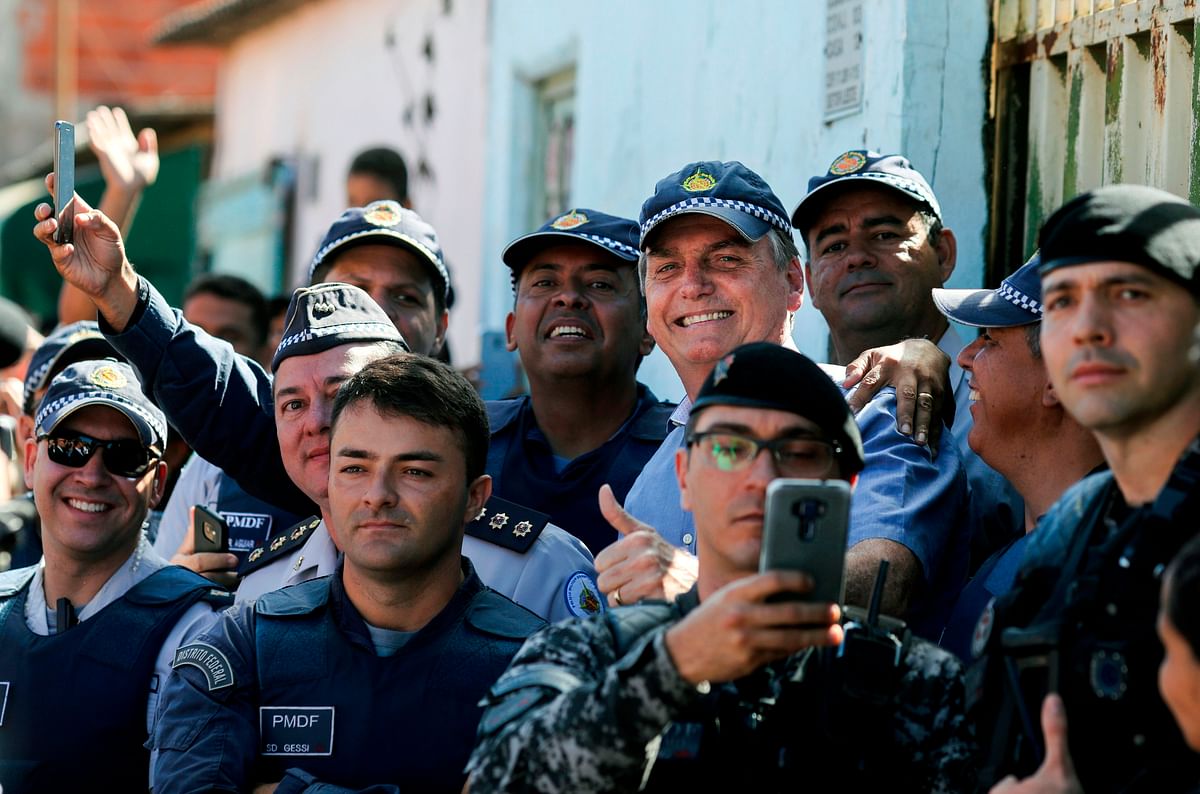 Brazilian president Jair Bolsonaro poses with members of the Federal District Police, in the outskirts of Brasília, Brazil, on 27 April 2019, during a visit to a family who had attended Easter ceremony at Planalto Palace. Photo: AFP