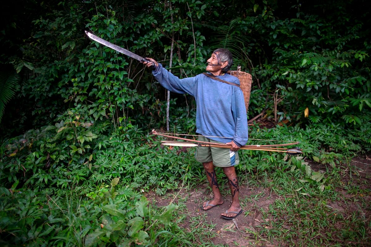 An Arara indigenous man points his way before a walk to collect bananas at the Laranjal tribal camp, in Arara Indigenous territory, in the northern Brazilian Amazon rainforest, on 15 March 2019. Photo: AFP
