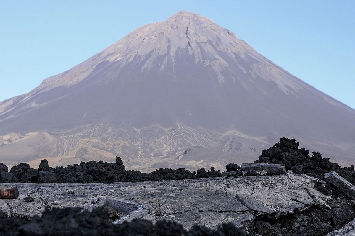 This picture taken on 31 March 2019, shows the volcano Pico do Fogo and the remains of the roof of a house submerged by lava during the last eruption in 2014, in the village of Portelo in Cape Verde`s Cha das Caldeiras valley. Photo: AFP