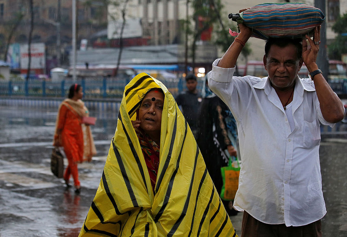 Commuters shelter from the rains as they cross a road in Kolkata, India, on 3 May 2019. Reuters