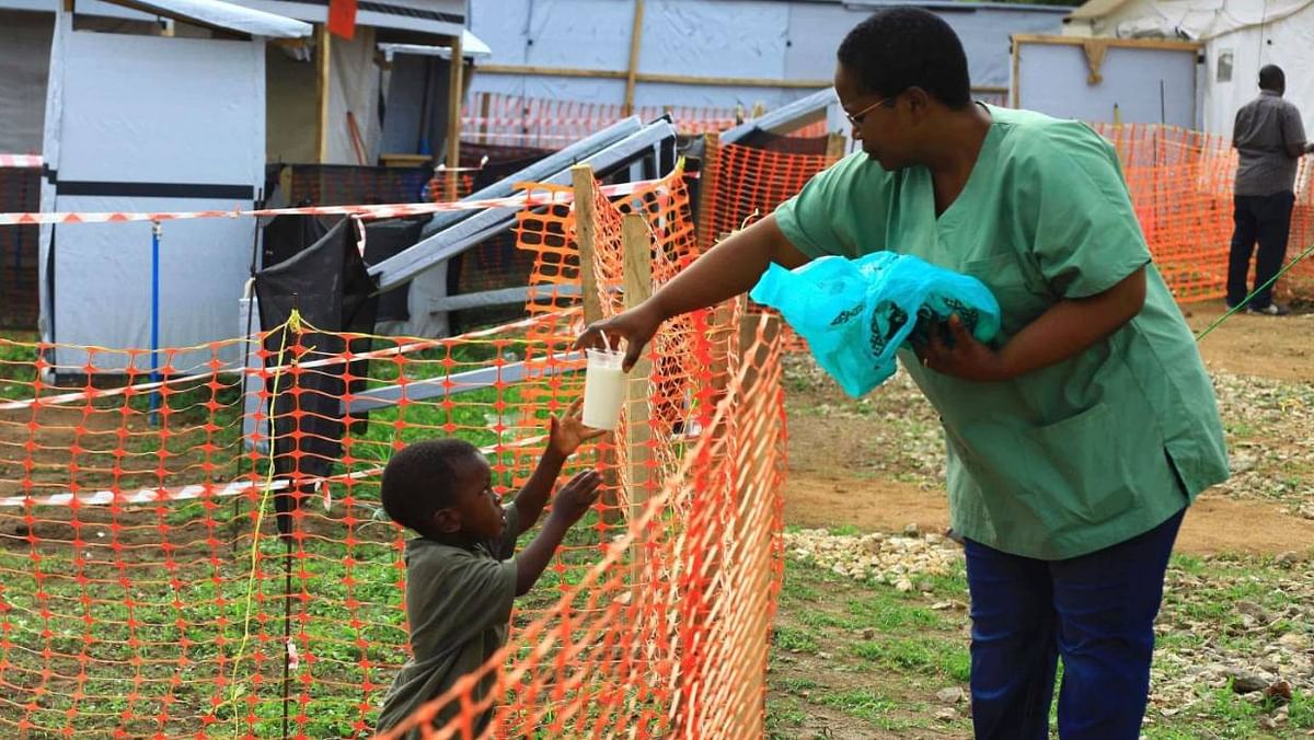 Health worker feeds a boy suspected of having Ebola. Photo: AP