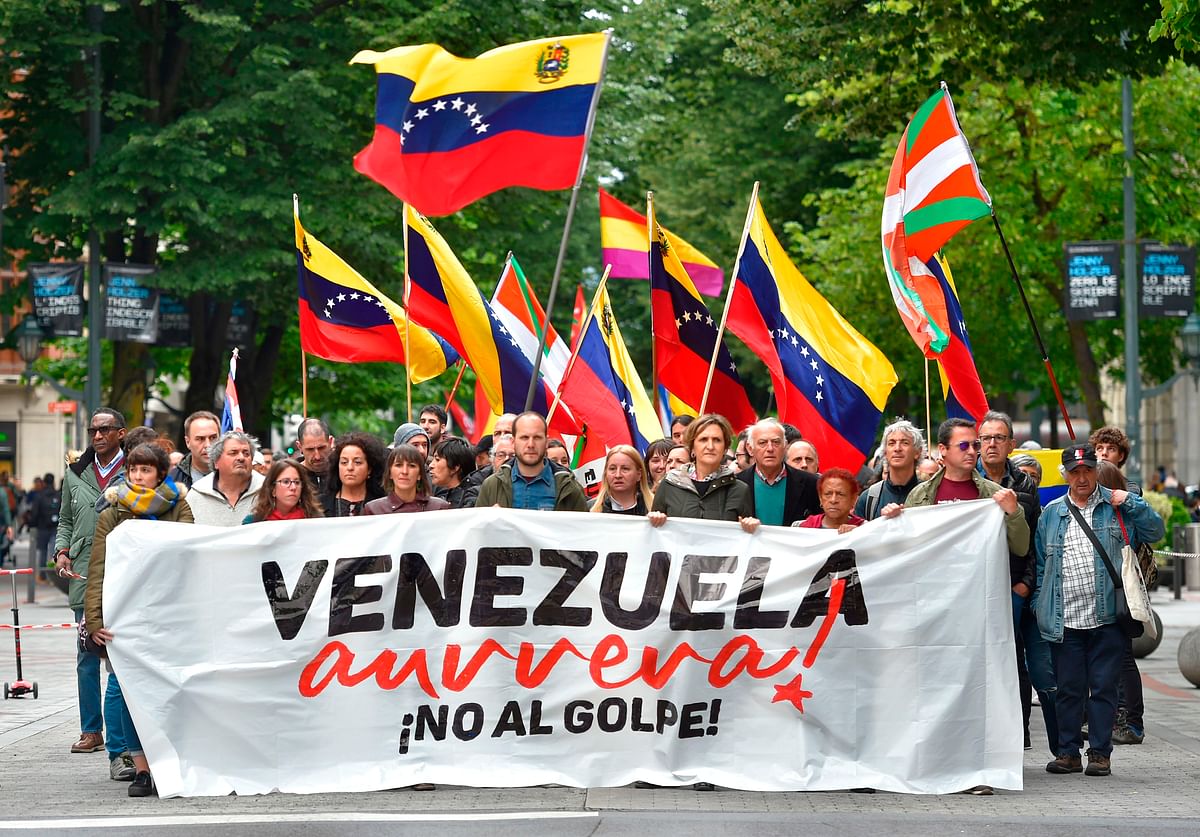 People wave Venezuelan flags as they march behind a banner reading `Go, Venezuela!. No to the coup d`etat!` during a demonstration in support of Venezuelan president Nicolas Maduro`s government in the Spanish Basque city of Bilbao on 4 May. Photo:AFP