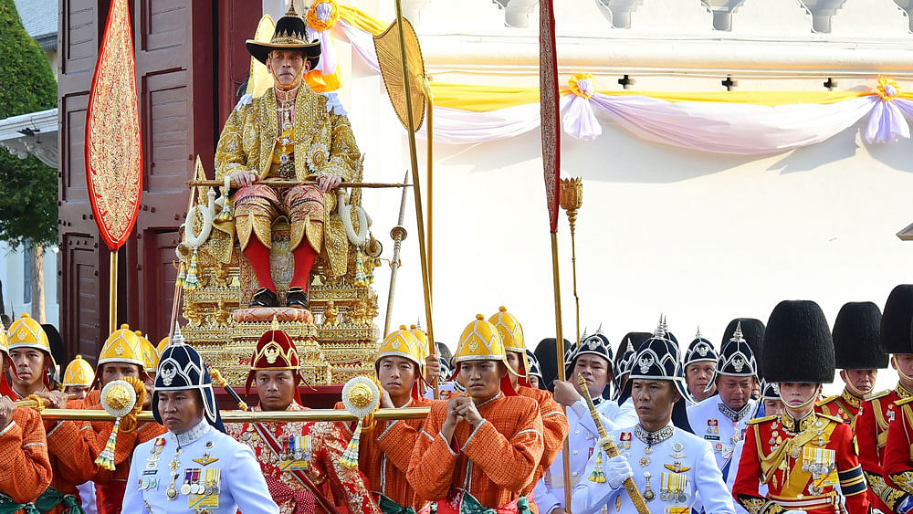 This handout from the Thai Royal Household Bureau taken and released on 5 May 2019 shows Thailand`s Queen Suthida (front R) marching beside the golden palanquin of King Maha Vajiralongkorn as it is carried out of the Grand Palace for his coronation procession in Bangkok. Photo: AFP