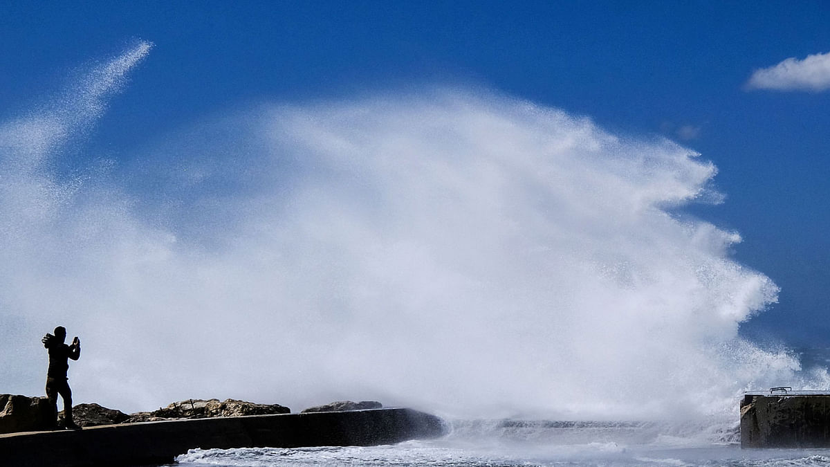 2A person stand on dam taking pictures as heavy waves hit the shore at the Plage du David beach in downtown Marseille, as storm Eleanor hits southern parts of France on 5 May 2019. Photo: AFP