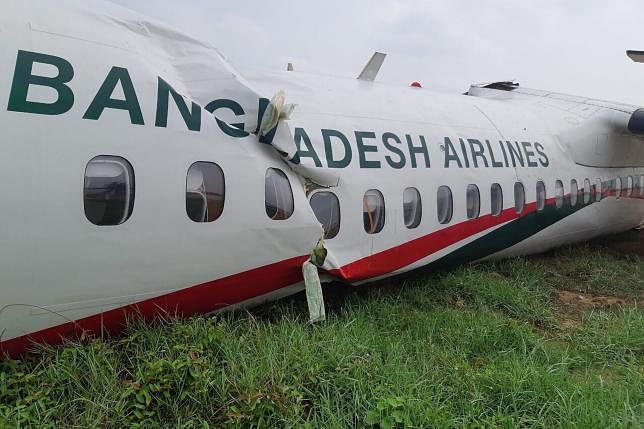 This handout picture taken and released by Myanmar Department of Civil Aviation on 9 May 2019 shows a crumpled Biman Bangladesh Airlines jet lying on the grass at the side of the Yangon International airport’s runway. AFP File Photo