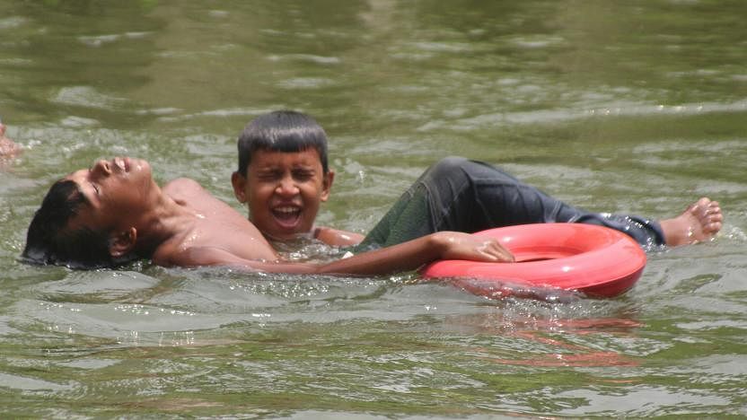 Boys swim at a pond in Katiadi upazila parishad office in Kishoreganj amidst scorching heat on Friday. Photo: Tafsilul Aziz.