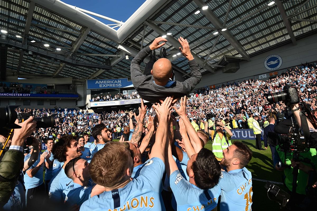 Manchester City's Spanish manager Pep Guardiola is thrown into the air by his players as they celebrate after their 4-1 victory in the English Premier League football match between Brighton and Hove Albion and Manchester City at the American Express Community Stadium in Brighton, southern England on 12 May, 2019. Photo: AFP