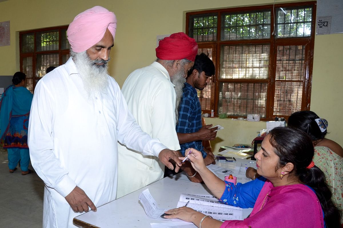 An Indian election official (R) marks the finger of voter Darshan Singh (L) as he prepares to cast his ballot at a polling station in a village on the outskirts of Amritsar on 19 May 2019, during the 7th and final phase of India`s general election. Photo: AFP