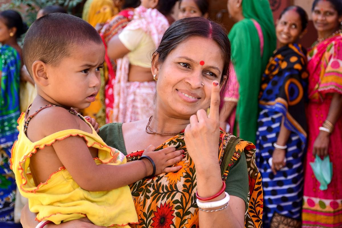 Indian voter Salona Haldar (C) shows her ink-marked finger as she holds her baby after casting her vote at a polling station in a village on the outskirts of Amritsar on 19 May. Photo: AFP