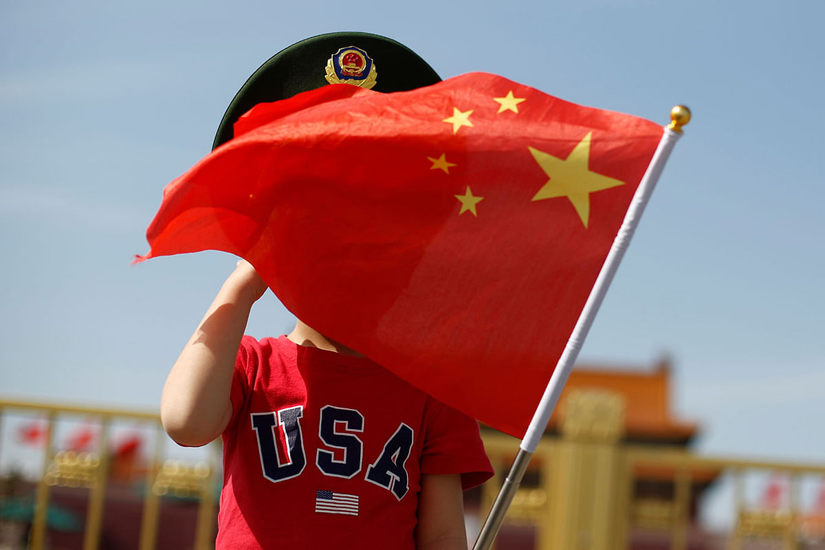 A boy wearing an US t-shirt waves a Chinese national flag in Tiananmen Square in Beijing, China on 7 May. Photo: Reuters