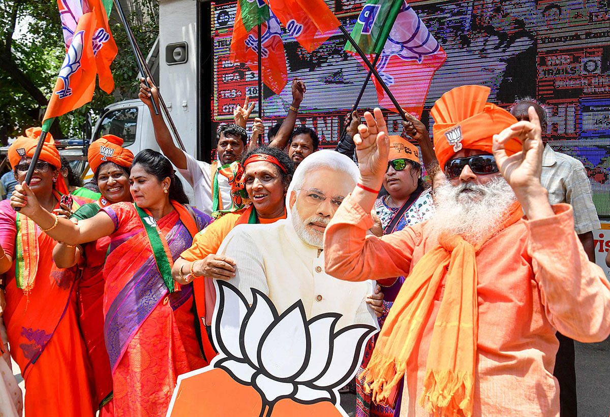 Indian supporters and party workers of Bharatiya Janata Party (BJP) dance and hold flags as they celebrate on the vote results day for India`s general election in Bangalore on 23 May 2019. AFP